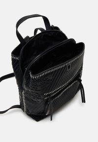 Schwarzer Rucksack mit gestepptem Muster, versehen mit floralem Prägung und zwei vorderen Reißverschlusstaschen. Enthält silberne Beschläge und zwei verstellbare Träger.