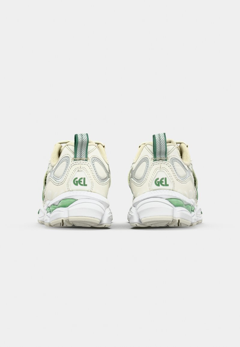 Baskets de sport beiges et vertes avec des superpositions en maille et des accents texturés ; présentent un logo GEL et un design de semelle intermédiaire blanche rembourrée.