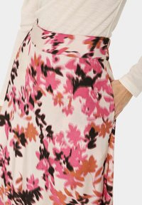 Gėlių sijonas su plačiu juosmeniu, puoštas rožinėmis, juodomis ir rudos spalvos raštais ant kreminio fono. Pagamintas iš lengvos medžiagos, sklandžios tekstūros.