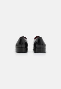 Scarpe oxford nere in vernice con una finitura liscia, punta arrotondata e un tacco leggero. Rivestimento interno rosso con marchio impresso.