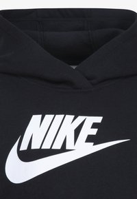 Juodas džemperis su dideliu baltu "NIKE" logotipu ir swoosh dizainu. Pagamintas iš minkštos medžiagos, su klasikiniais apvaliais kaklo geležtėmis ir pritvirtinta kapucha.