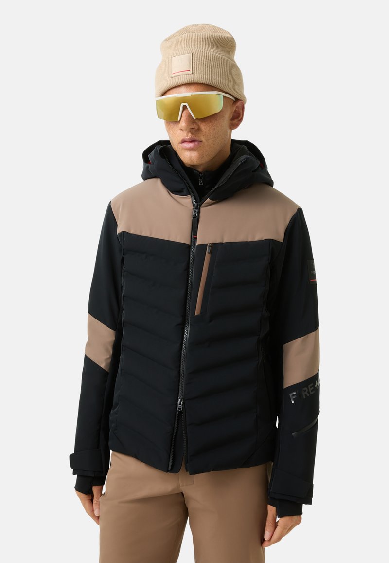 Schwarz-beige Pufferjacke mit Kapuze, ausgestattet mit einer Reißverschlusstasche, elastischen Bündchen und reflektierenden Akzenten. Getragen mit einer beigen M�ütze und Sonnenbrille.