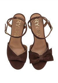 Sandali con tacco in suede marrone, dotati di una fascia ampia e di un'accentatura a fiocco. Presentano cinturini alla caviglia regolabili e una soletta texture per il massimo comfort.
