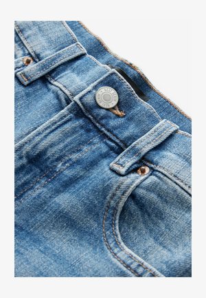 Lyseblå denimjeans med en sølvknap og kontrasterende orange syning. Har en forlommer og en bæltestrop. Syningen er synlig.