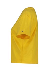 Gul bomullströja med korta ärmar, rund halsringning och en liten logotypdetalj på ärmen. En enkel, boxig design.