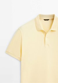 Polo jaune clair à manches courtes avec col et patte boutonnée, vu de face sur fond blanc.