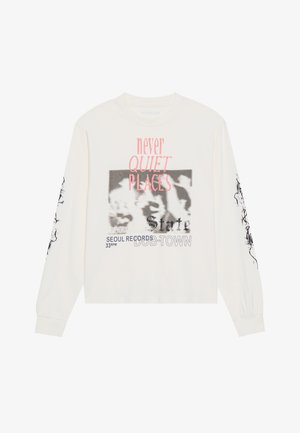 Crème katoenen t-shirt met lange mouwen, voorzien van een voorzijde grafiek met roze en zwarte tekst en geprinte accenten op de mouwen. Gekorte ontwerp.