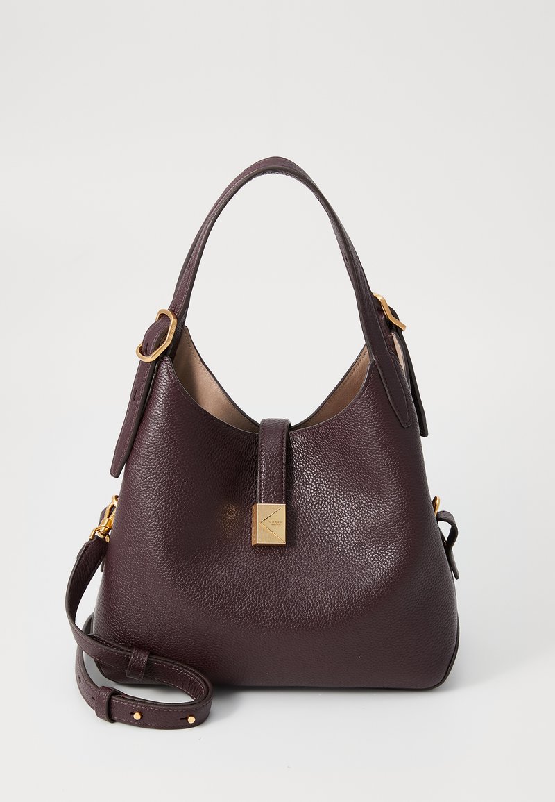 Tamsiai burgundi spalvos odinė rankinė, su tekstūriniu paviršiumi, auksinės spalvos detalėmis ir nuimamą petnešą.