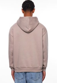 Hoodie in lichtbeige, met een relaxte pasvorm, ribbelboorden en een ribbelzoom. Gladde, zachte textuur zonder zichtbare versieringen.