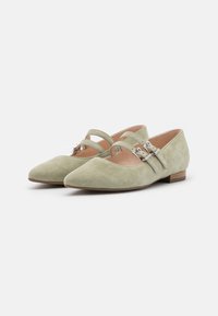 Ballerines en suède vert avec bout pointu, présentant deux sangles décoratives et des accents de boucles en argent. Talon en bois bas, doublure intérieure lisse.