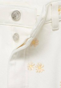 Tissu en denim blanc avec des fleurs marguerites brodées jaune clair, comportant des accessoires en argent et une surface légèrement texturée.