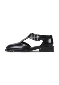 Schwarze Ledersandalen mit einem Ausschnittdesign, einem Riemen mit einer silbernen Schnalle und kleinen silbernen Nieten entlang der Sohle. Flacher Absatz.