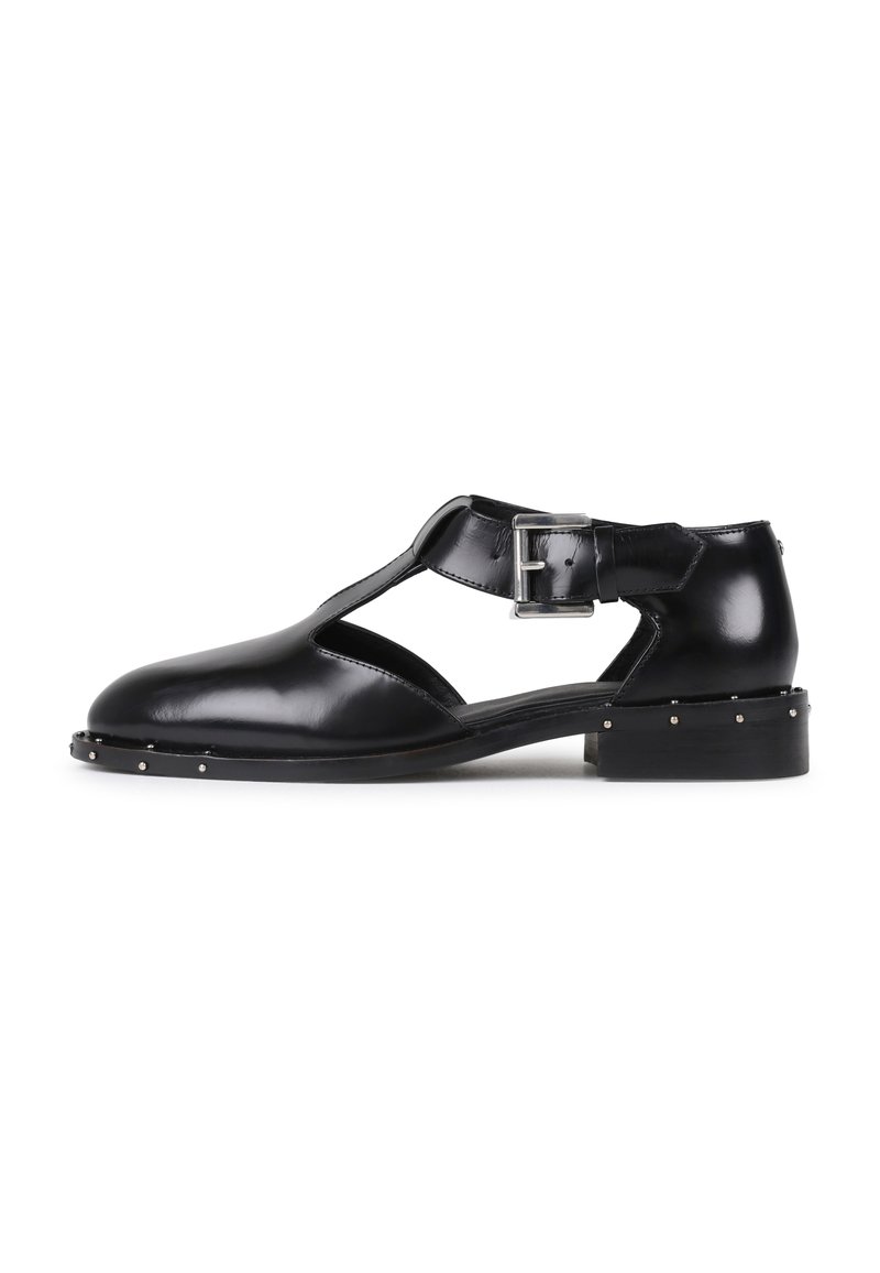 Schwarze Ledersandalen mit einem Ausschnittdesign, einem Riemen mit einer silbernen Schnalle und kleinen silbernen Nieten entlang der Sohle. Flacher Absatz.