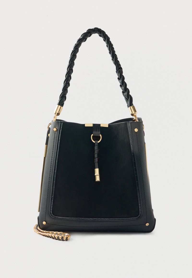 Mustast siledast nahast käekott punutud rihmaga, kuldse tooniga riistvara, ristkülikukujuline ja külje peal kettaktsendiga.