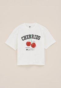 Balta trumpa rankovėmis marškinėliai, kuriuose pavaizduota "ČERIES" grafika su dviem raudonomis vyšniomis, žaliais stiebais ir žaismingu tekstu juoda ir raudona spalvomis.