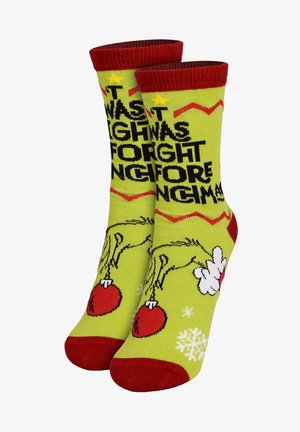 Calzini verdi con testo nero, accenti rossi e immagini di ornamenti e fiocchi di neve, dal tema festivo e divertente.