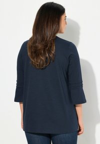 Top blu navy con maniche a tre quarti, dal fit rilassato, con scollatura rotonda e dettagli con risvolto. Tessuto dalla texture morbida.