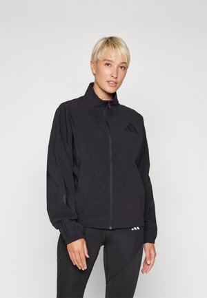 Black lightweight windbreaker jacket with a high collar, zip closure, and elastic cuffs. Features subtle branding on the chest and sleeves.