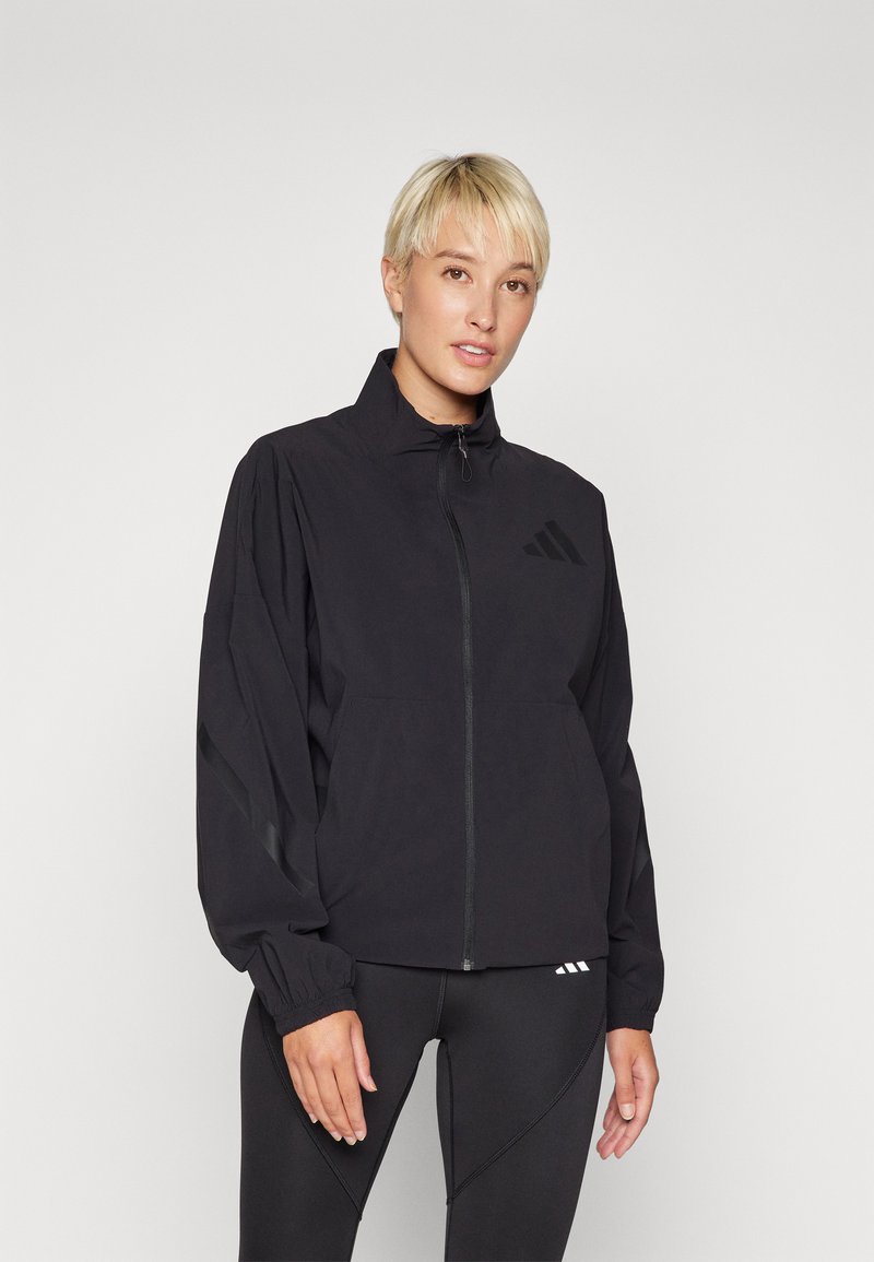 Black lightweight windbreaker jacket with a high collar, zip closure, and elastic cuffs. Features subtle branding on the chest and sleeves.