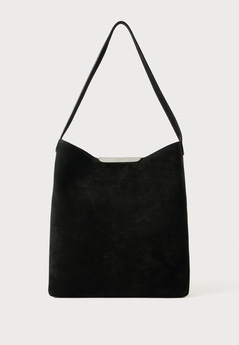 Bolsa de ombro em camurça preta com uma textura suave, design minimalista e um detalhe em metal prateado na parte superior. Apresenta uma abertura ampla.