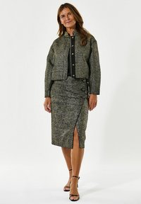 Getextureerde zwart-gouden two-piece outfit met een cropped jas met knopen en een knie-lange rok met een zijopening en knoopdetail.