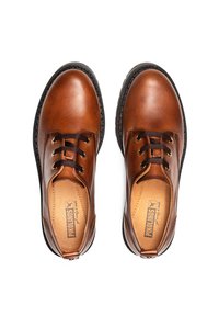 Chaussures en cuir marron avec une finition lisse, bout rond, semelles en caoutchouc noires et lacets marron, arborant un logo sur la semelle intérieure.