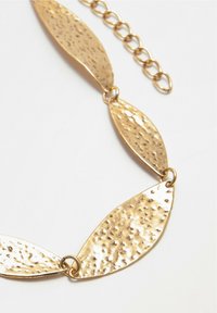 Collana in oro con pendenti a forma di foglia allungata e testurizzata, con finitura martellata, connessi da anelli circolari. Catena regolabile.