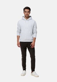 Helles graues Hoodie mit Kordelzügen, Fronttasche; getragen mit dunklen Jeans und weißen Sneakers. Minimalistisches Design, weiche Textur.