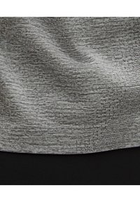 Grått texturerat tyg med ett subtilt mönster, som har en slät och mjuk yta, lager ovanpå ett solidt svart material nedanför.