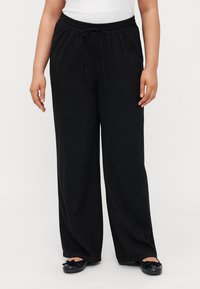 Pantalons larges noirs avec une taille élastique et cordon de serrage. Fabriqués en tissu doux et léger. Présentent des poches latérales pour plus de commodité.