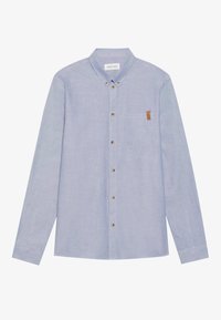 Chemise bleu clair à manches longues, boutonnée, avec col boutonné et poche poitrine ornée d'une petite étiquette marron.