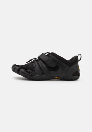 Chaussure noire Vibram FiveFingers pieds nus avec compartiments individuels pour les orteils, tige en maille et sangle Velcro ajustable sur fond blanc.