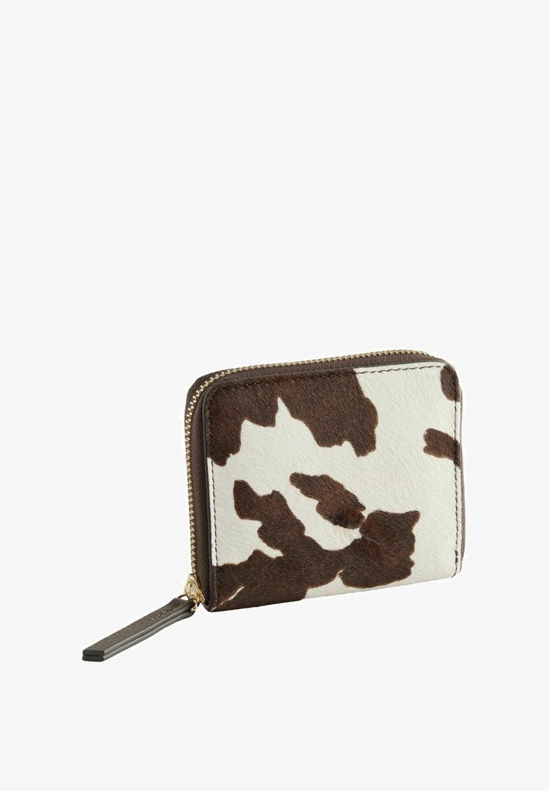 Billetera compacta con cierre de cremallera en patrón de piel de vaca marrón y blanco y una tira de cuero marrón oscuro en el tirador.
