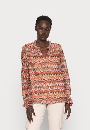 Blusa de manga longa em padrão zigzag multicolorido, com decote com babados e punhos elásticos, apresentando tons de laranja, rosa e castanho.