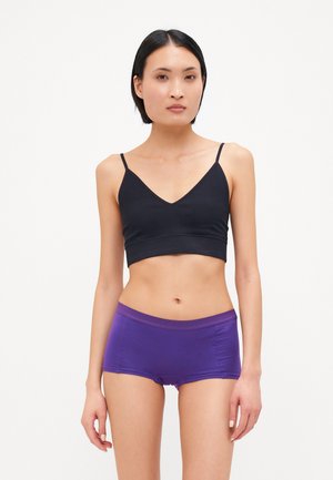 Bralette in cotone nero con spalline sottili, abbinato a boxer in cotone viola con un ampio cinturino in vita. Texture liscia, design aderente.