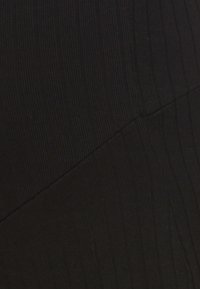 Crna pamučna suknja s vertikalnom rebrastom teksturom, koso krojenim šavovima i uskim dizajnom, ističući elegantnu siluetu.