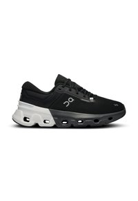 Chaussure de sport noire avec une tige texturée, dotée d'une semelle rembourrée blanche et grise et de trous d'air bien visibles sur le dessous.