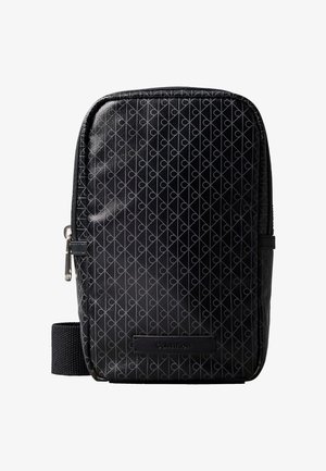 Sac bandoulière Calvin Klein noir avec motif géométrique diagonal et fermeture à glissière, doté d'une sangle en tissu et d'un patch logo.