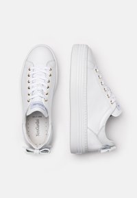 White sneakers made of smooth leather featuring a thick, textured sole, decorative gold eyelets, and a small bow accent at the heel.