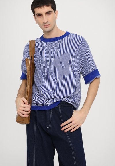 Blå og hvid stribet strikket skjorte med løs pasform, korte ærmer og ribbet krave. Kombineret med mørke denim bukser.