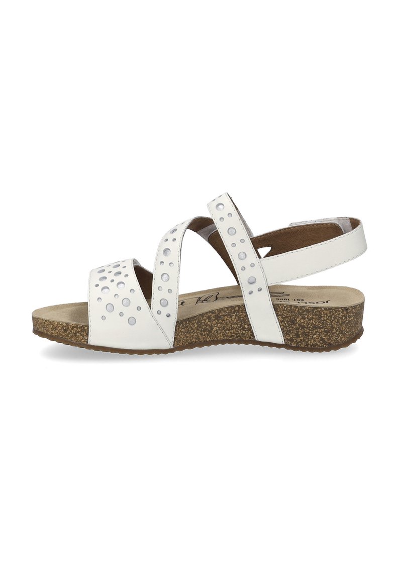 White leather sandals featuring three crisscross straps adorned with round studs, a cushioned cork sole, and a low heel design.