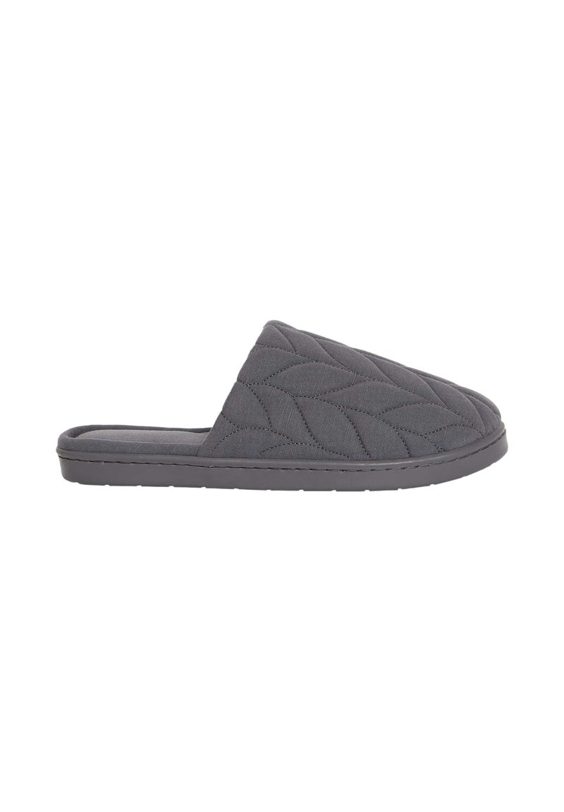 Zapatilla gris acolchada con una textura suave, parte trasera abierta y una suela de goma plana. Presenta un patrón de hojas bordado en la parte superior.