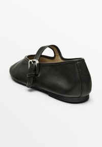 Schwarzer Lederschuh mit glatter Oberfläche, runder Zehenform und seitlichem Schnallenriemen; flache Sohle und offenes Fersen-Design.