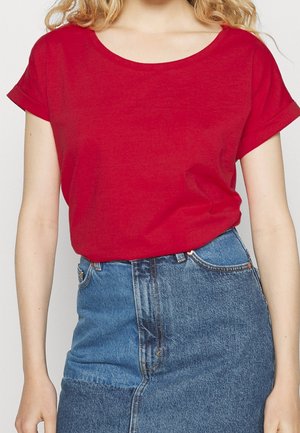 Czerwona bawełniana koszulka z okrągłym dekoltem i podwiniętymi krótkimi rękawami, zestawiona z jeansową spódnicą o wysokim stanie w odcieniach niebieskiego.