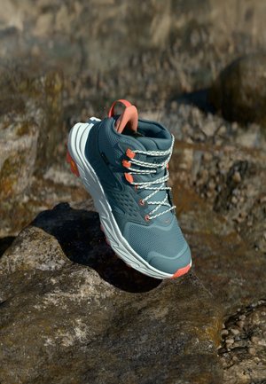 Botas de caminhada para homens, impermeáveis, com parte superior em verde-água com acabamento texturizado e detalhes em laranja, entressola branca que contrasta e solado de borracha robusto.