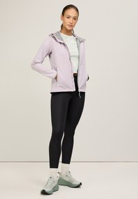Hellblau-gestreifte Kapuzenjacke mit grauen Akzenten, seitlichen Taschen, kombiniert mit schwarzen Leggings und mintgrünen Turnschuhen. Einfaches Design und glatte Textur.