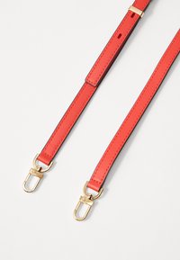 Cinghia di borsa in pelle rossa con accessori in tono oro, dotata di due chiusure a clip, una superficie liscia e dettagli di cucitura a contrasto.