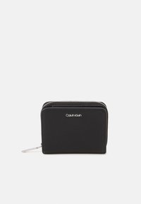Calvin Klein black wallet in textured fabric, featuring a zip closure and silver-tone logo. Compact rectangular shape with a sleek design.