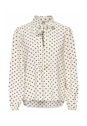 Blouse blanche à manches longues à pois noirs, patte de boutonnage devant, poignets élastiques et col avec un nœud.