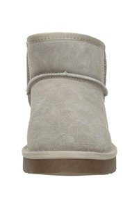 Beige suède enkellaarsjes met een ronde neus, gestikte details en een rubberen zool. Geen zichtbare versieringen of kenmerkende patronen.